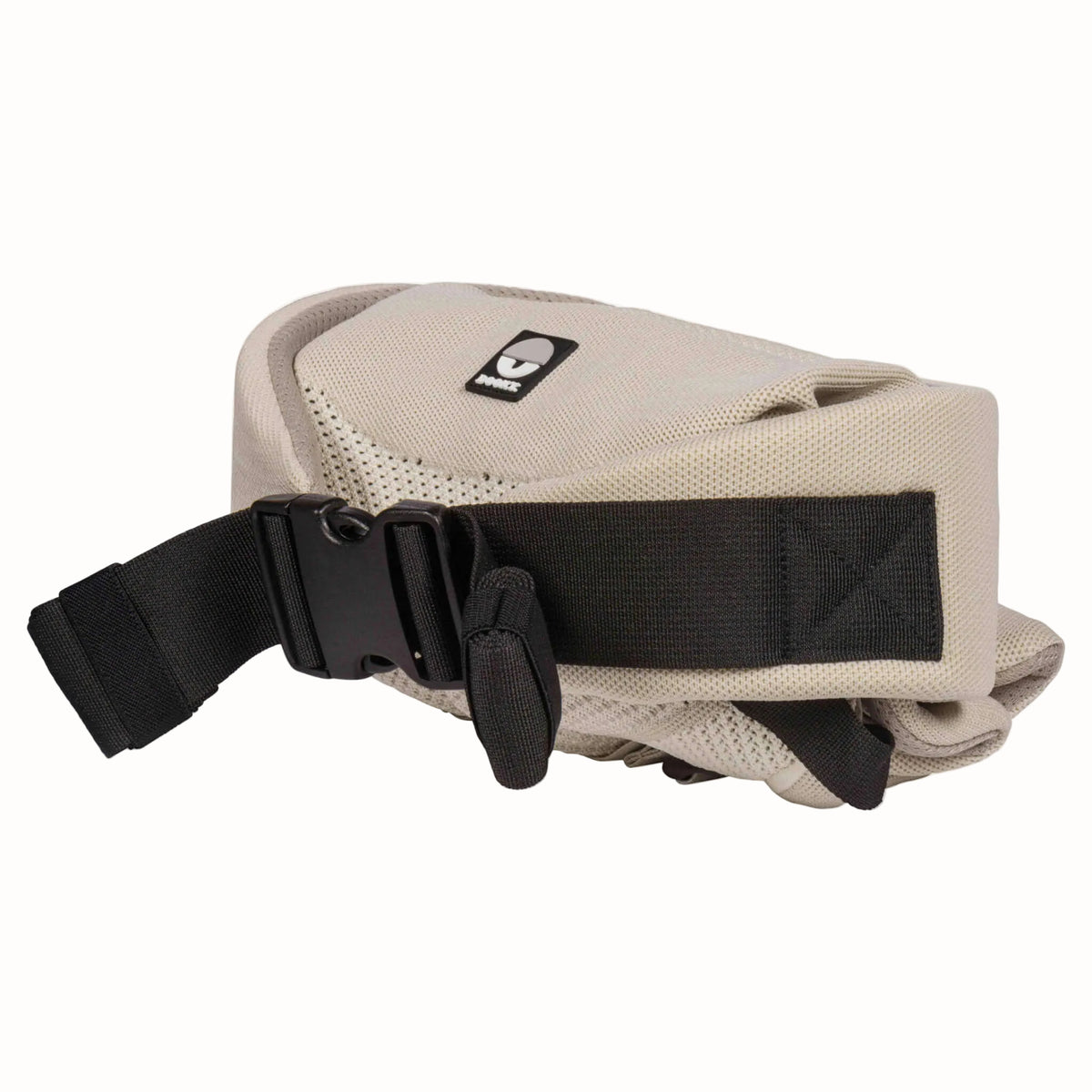 Beige baby carrier folded into a compact shape, showing the adjustable black waist buckle and securing strap.