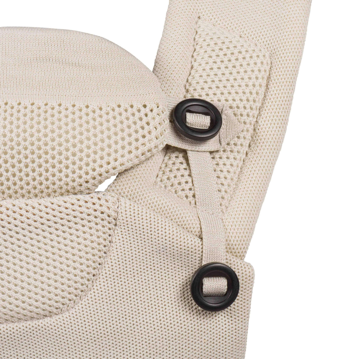 Close-up of the beige baby carrier shoulder strap and adjustable head support attachments with black fastening loops.
