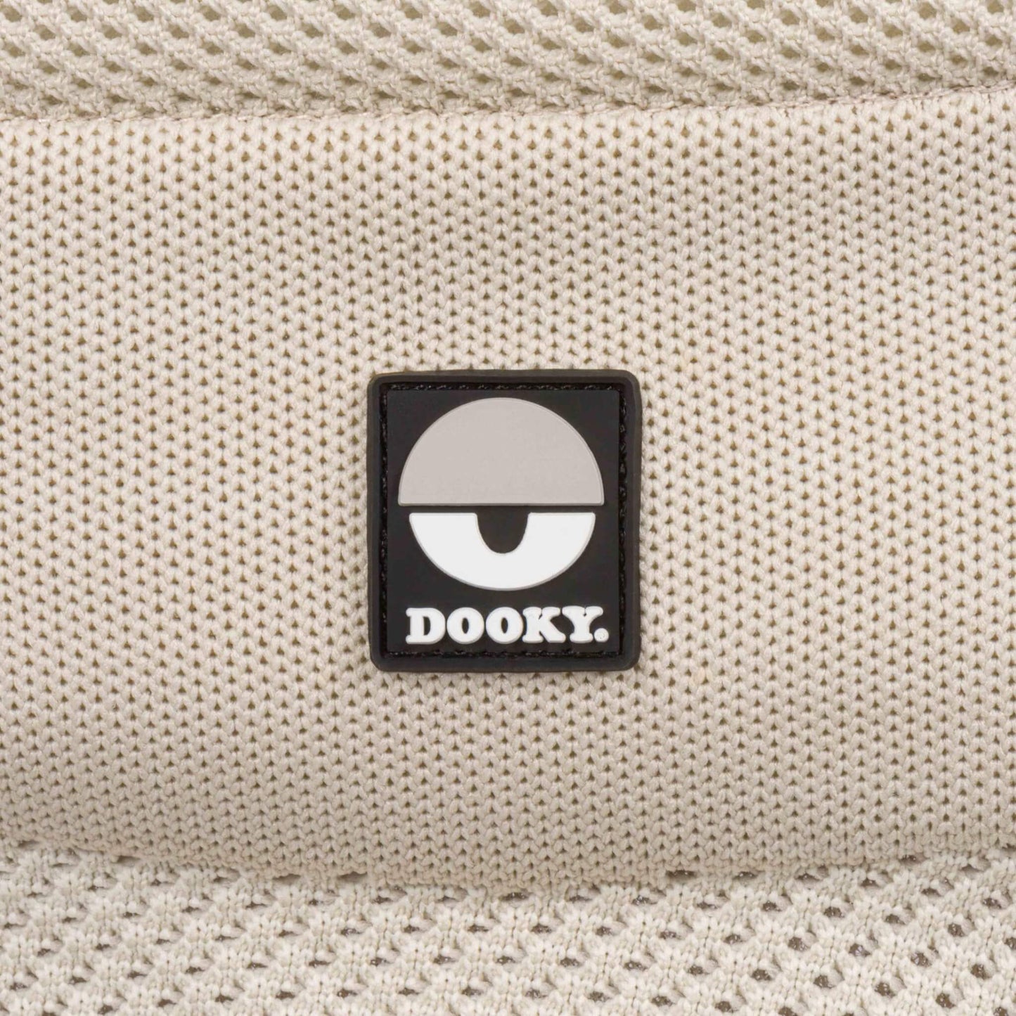 Close-up of the Dooky logo on the beige knitted fabric of the Terra Nova baby carrier.