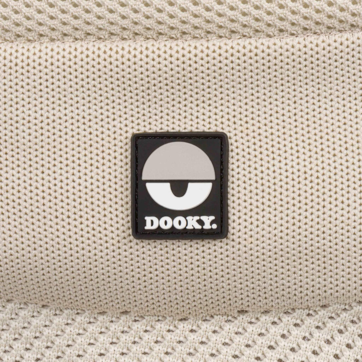 Close-up of the Dooky logo on the beige knitted fabric of the Terra Nova baby carrier.
