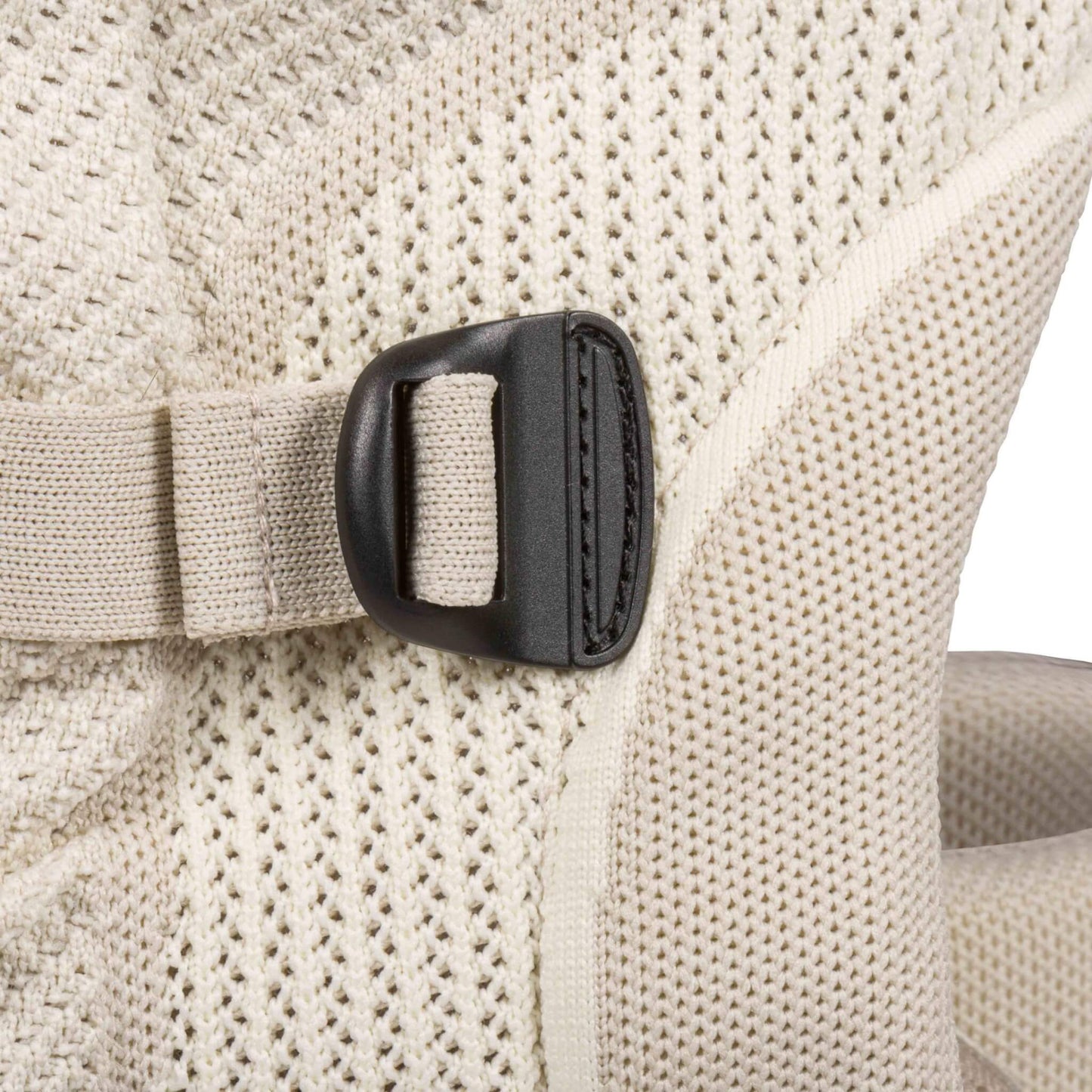 Close-up of an adjustable black buckle and beige strap on the breathable knitted fabric of a baby carrier.