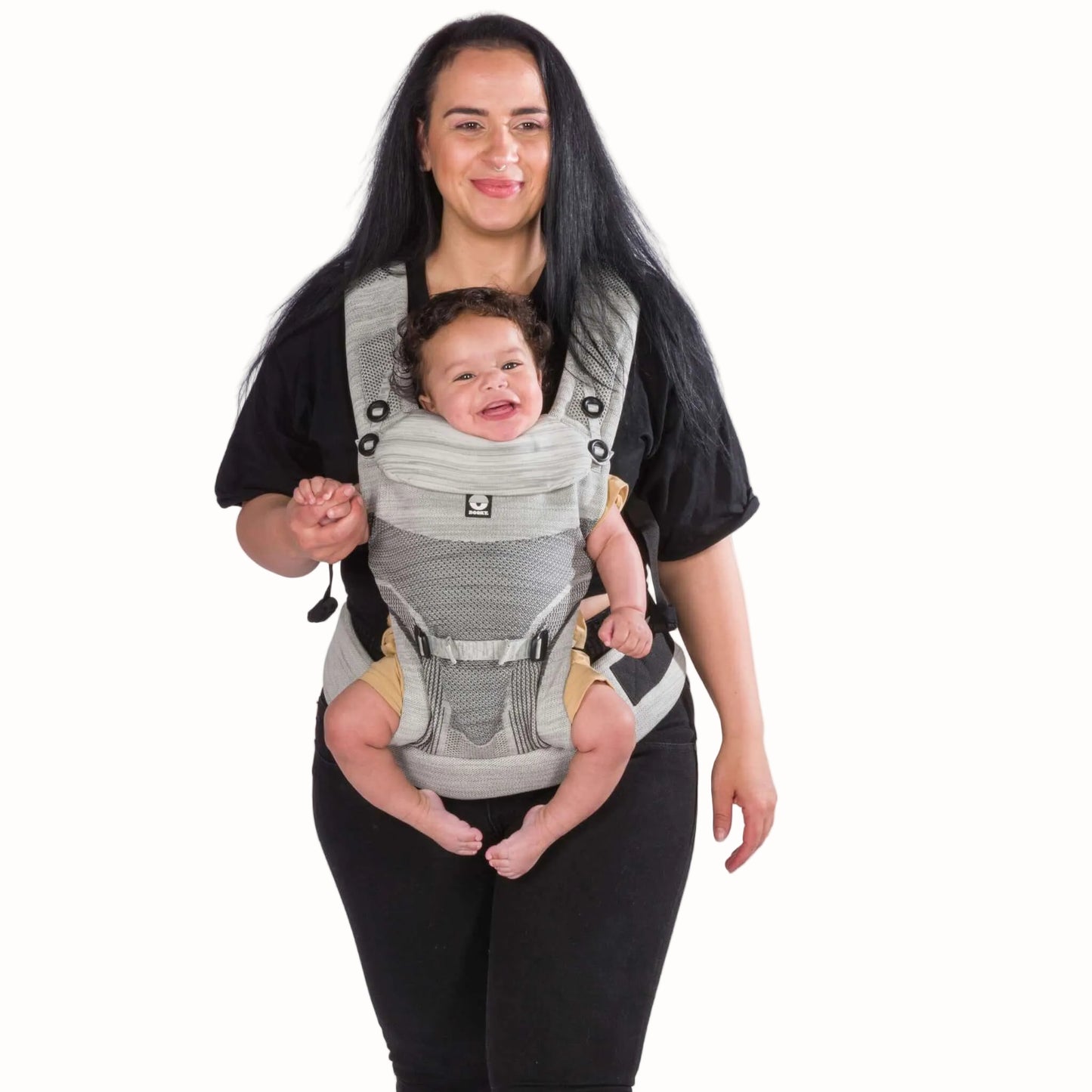 A parent carrying a baby facing outward in a grey baby carrier, with the baby supported in a seated position.