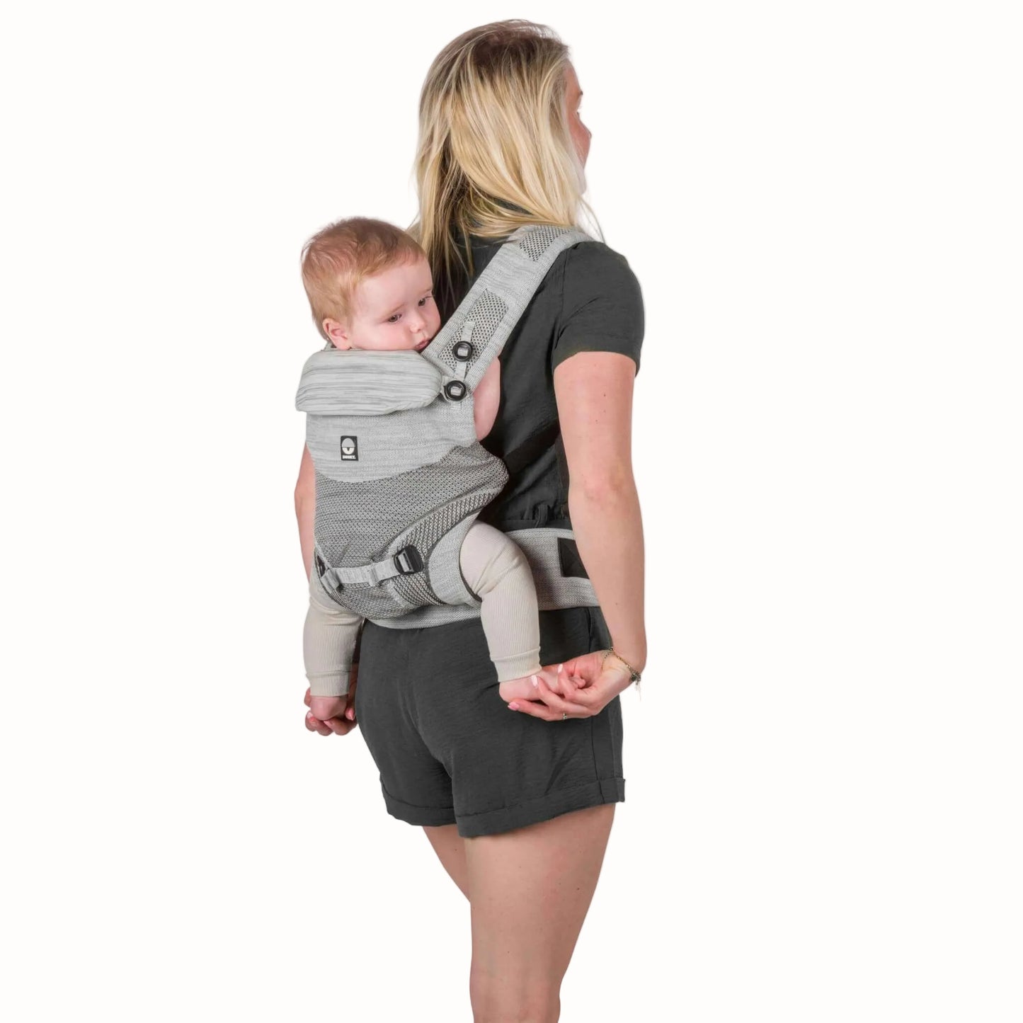 A parent carrying a baby on their back in a grey baby carrier, showing the supported back carrying position.