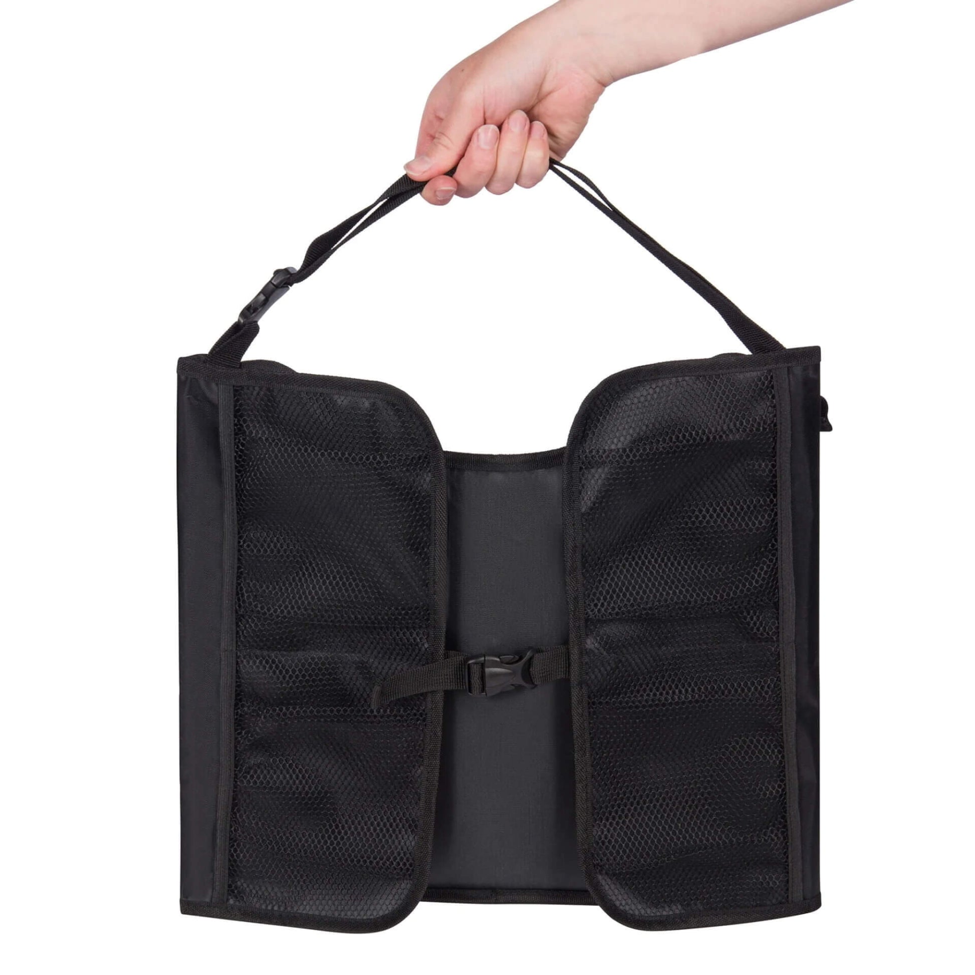 A folded black travel table with mesh pockets, carried by hand using the attached strap.