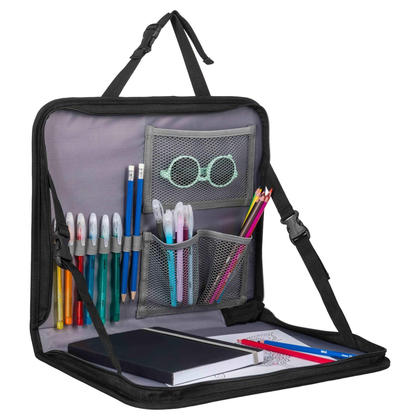 An open travel tray with mesh pockets filled with pencils, pens, a pair of sunglasses and a notebook resting on the tray surface.