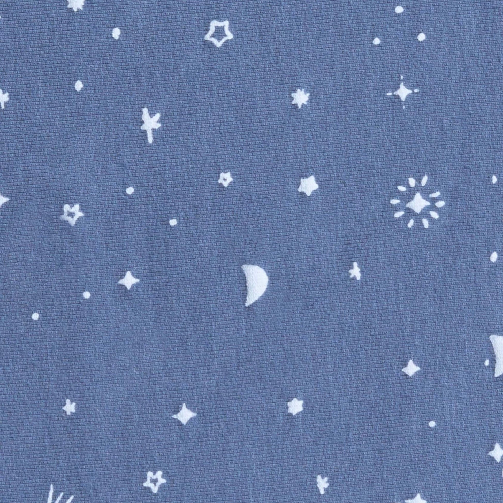 Close-up of blue jersey fabric with scattered white moon, star and comet pattern from the Night Sky babygrow design.