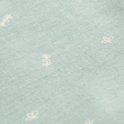 Close-up of Sage green jersey fabric with scattered white leaf and sprig motifs from the babygrow design.