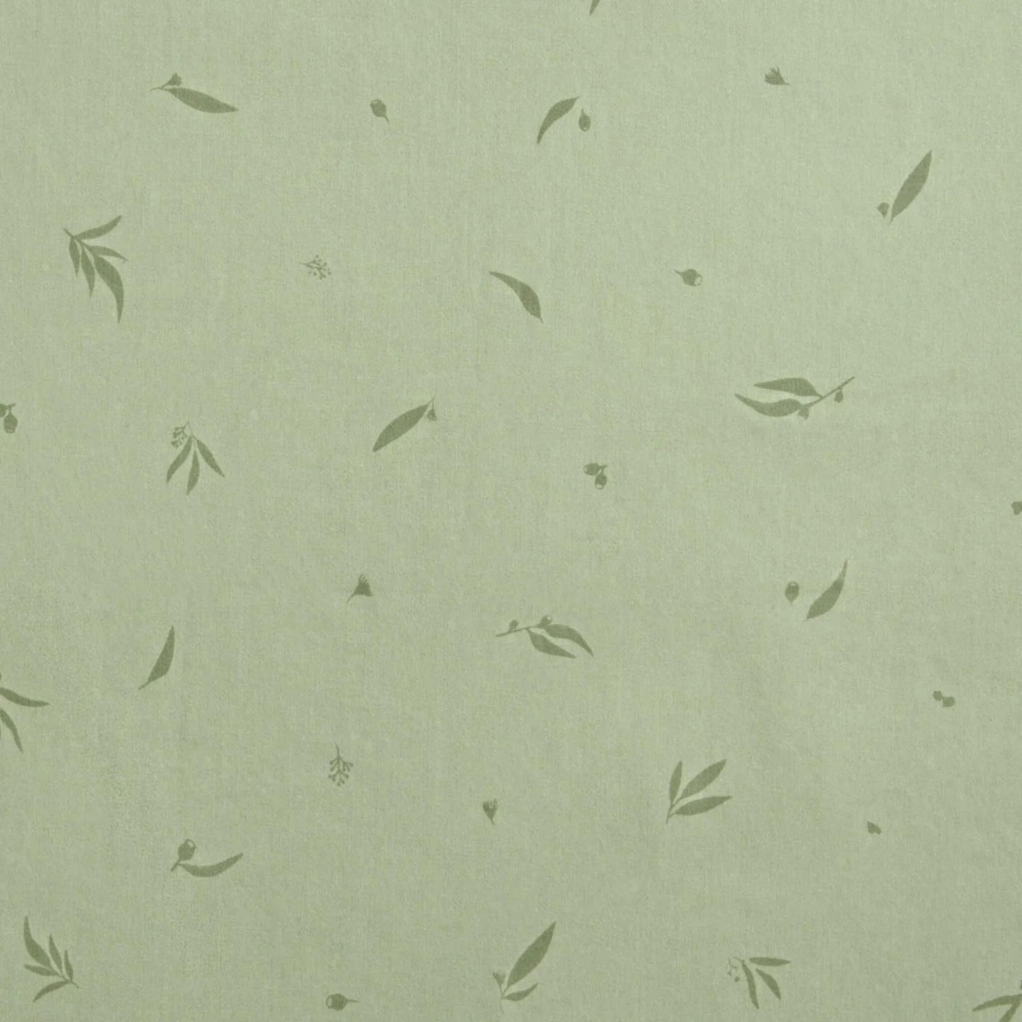 Close-up of soft green cotton fabric patterned with scattered leafy motifs, showing the Willow design print.