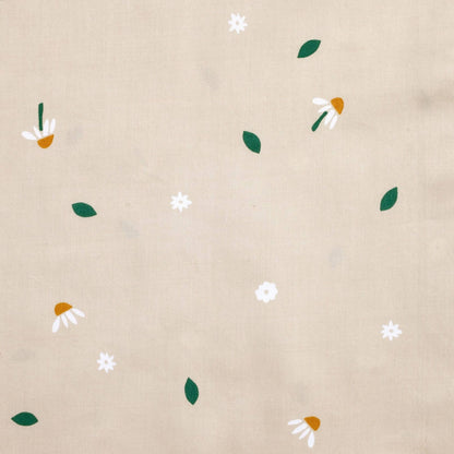Close-up fabric view of the Daisy Sprinkle fabric print featuring scattered white daisies, golden centres, and green leaves on a beige background.