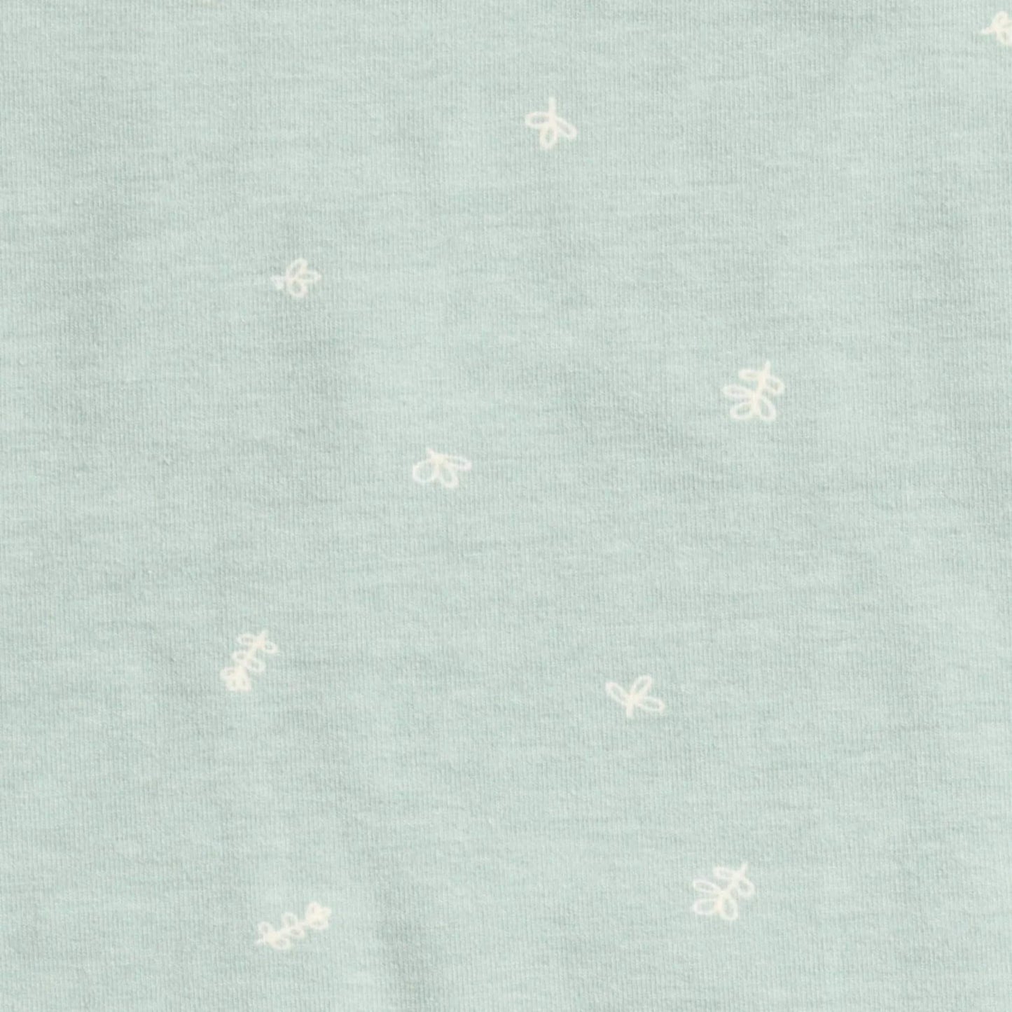 Close up of sage green organic cotton fabric with small white doodle prints across the material.