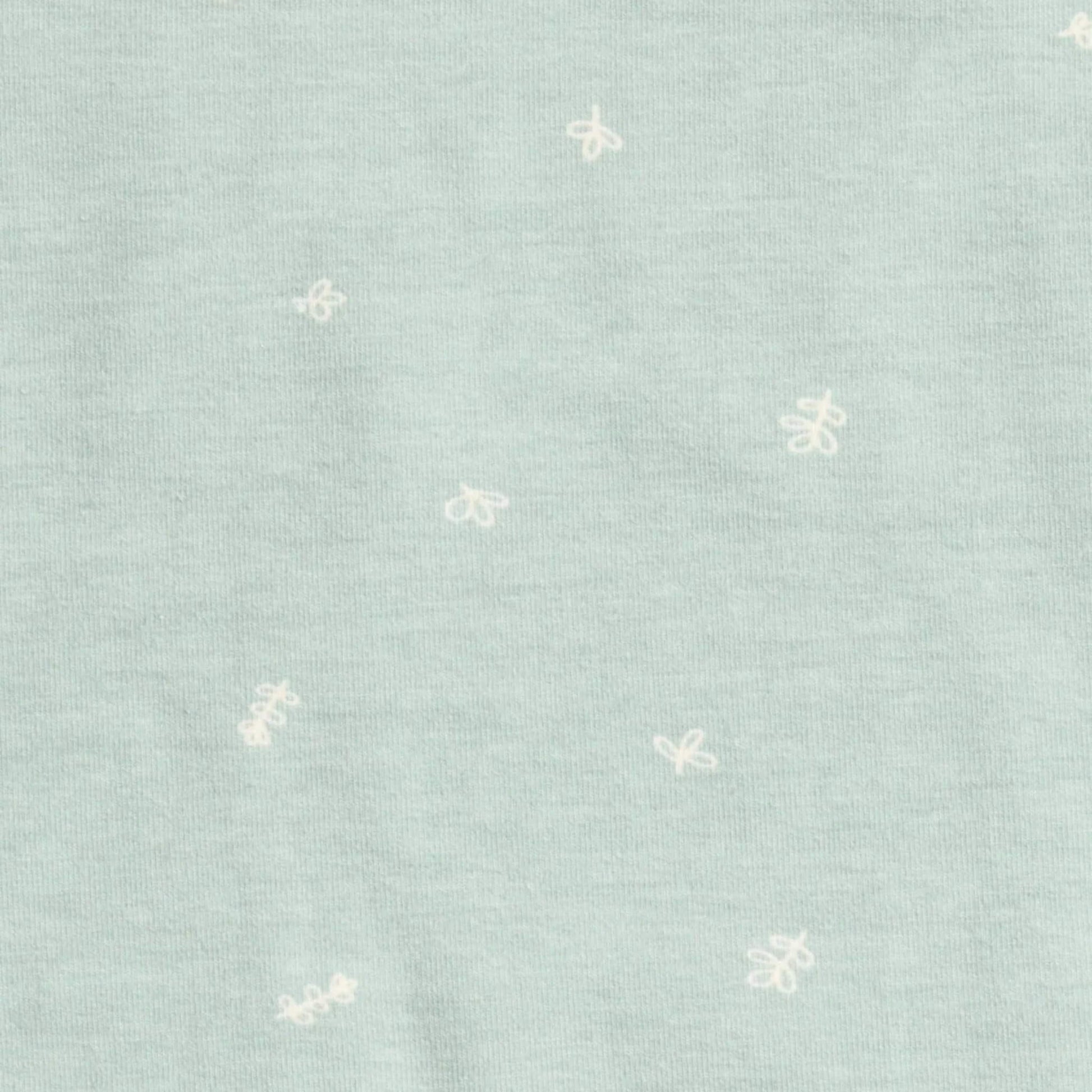 Close up of sage green organic cotton fabric with small white doodle prints across the material.