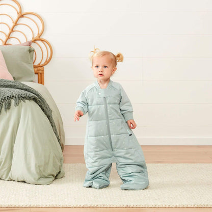 Toddler standing in a sage padded sleep suit bag with legs separated into suit mode.