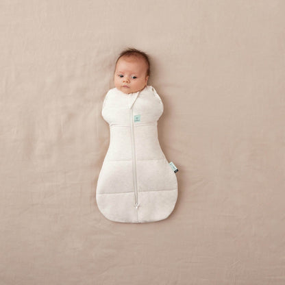 Baby in a winter TOG cocoon swaddle bag, oatmeal colour, organic and breathable fabric, perfect for keeping warm in colder weather.