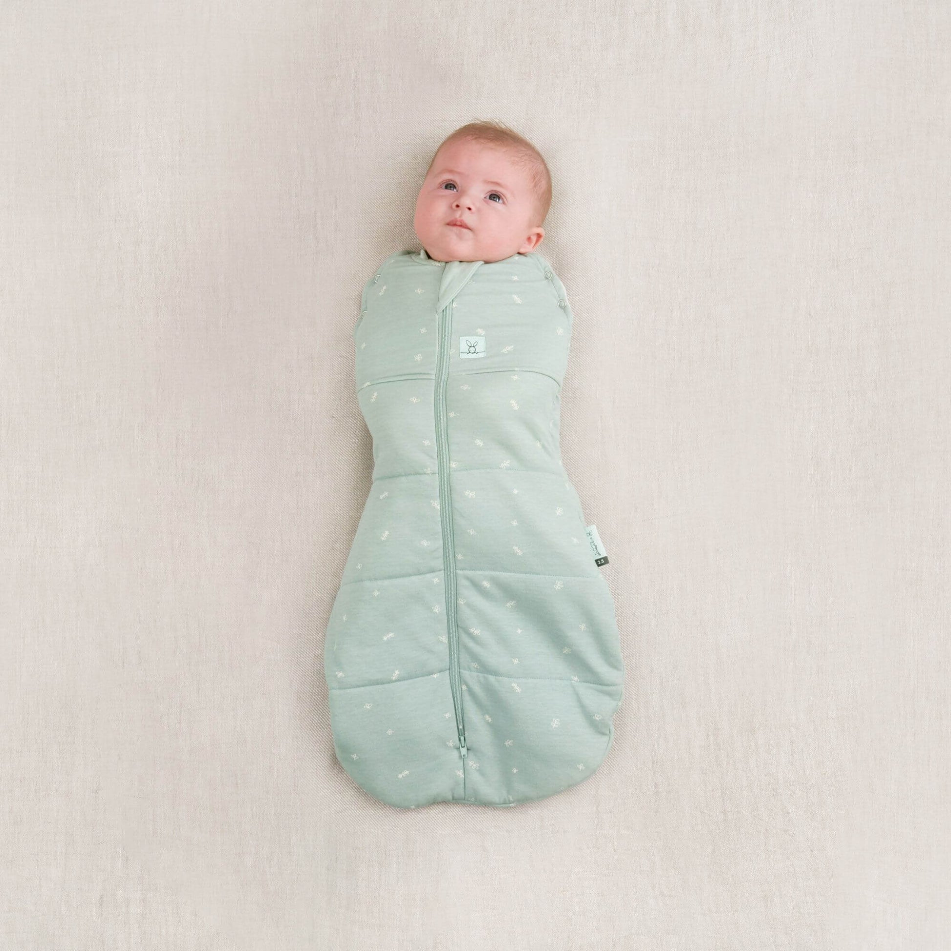 Baby in a winter weight 2.5 TOG cocoon swaddle bag, sage colour, organic and breathable fabric, perfect for keeping warm in colder weather.