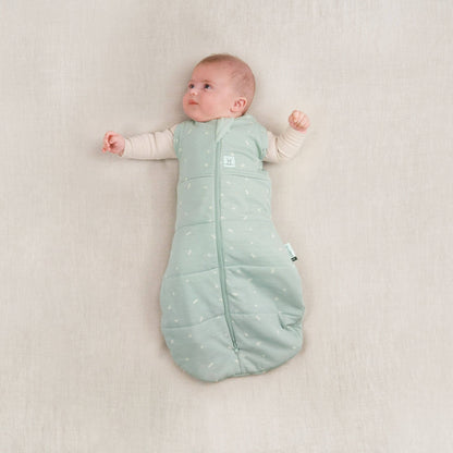 Baby lying in a winter weight 2.5 TOG cocoon swaddle bag, sage colour, both arms fully unswaddled.