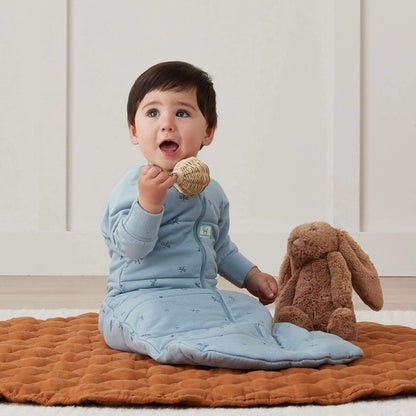 Toddler sitting comfortably in a winter weight sleeping bag in Dragonflies print, playing on a soft quilted mat.