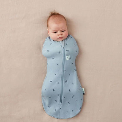 Baby Swaddle Bag in dragonflies print, showcasing a snug baby swaddled in breathable, soft blue organic cotton fabric.