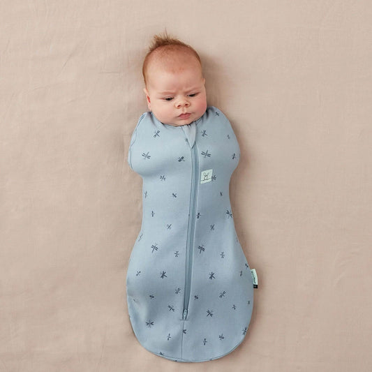 Baby Swaddle Bag in dragonflies print, showcasing a snug baby swaddled in breathable, soft blue organic cotton fabric.