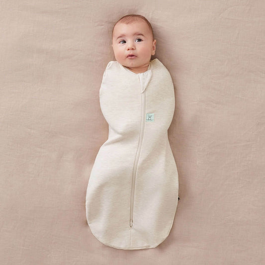 Baby snugly wrapped in a Cocoon Swaddle Bag in oatmeal, designed for secure and comfortable sleep, with a soft fabric finish.