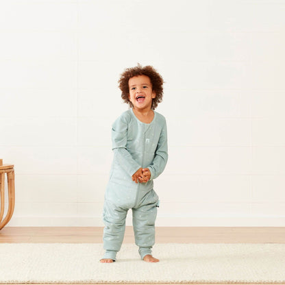Smiling toddler wearing a winter weight 2.5 TOG Sleep Onesie in sage green, showcasing its comfortable design and freedom of movement for active sleepers.