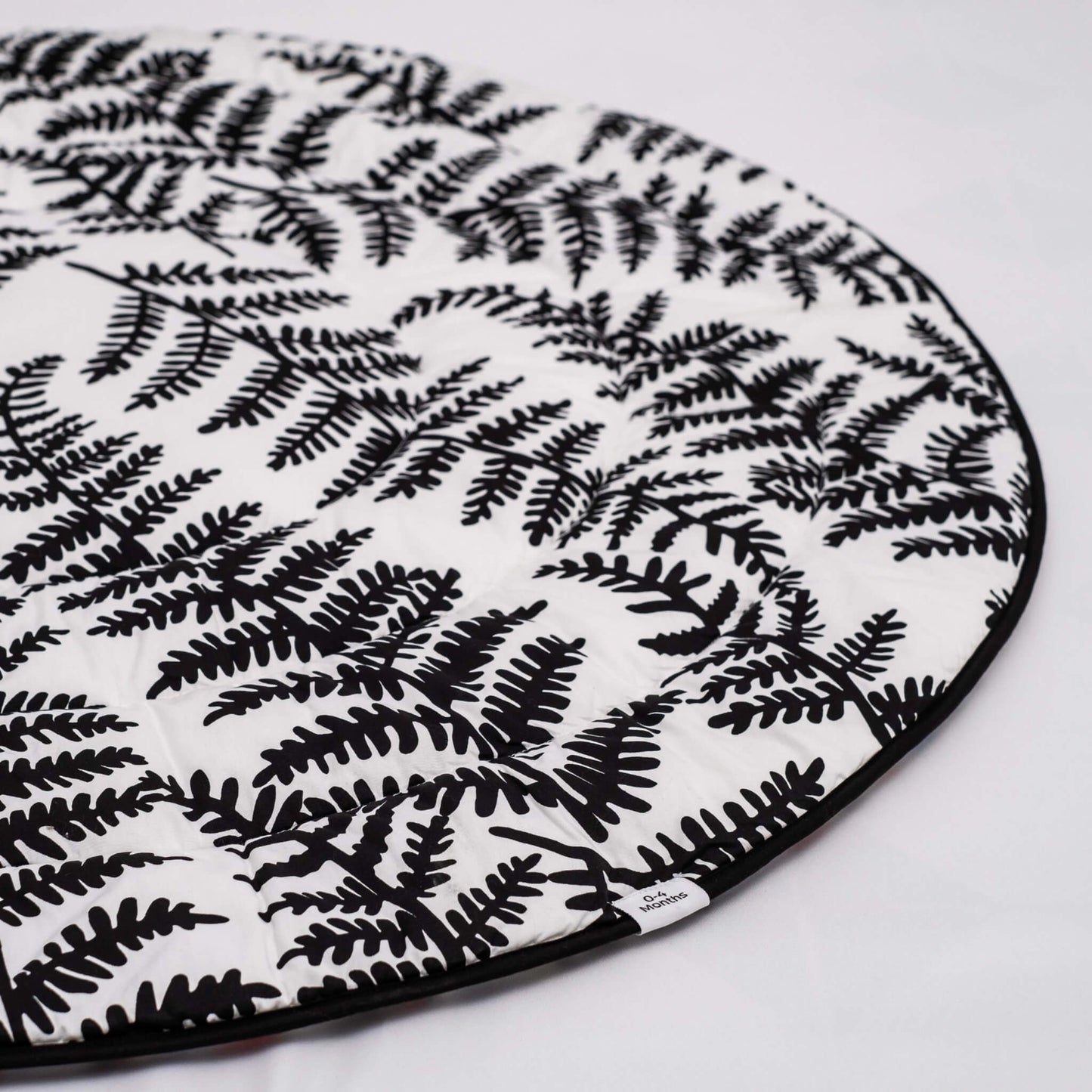 Detail of softly quilted organic cotton surface with black leaf shapes stitched across white background.