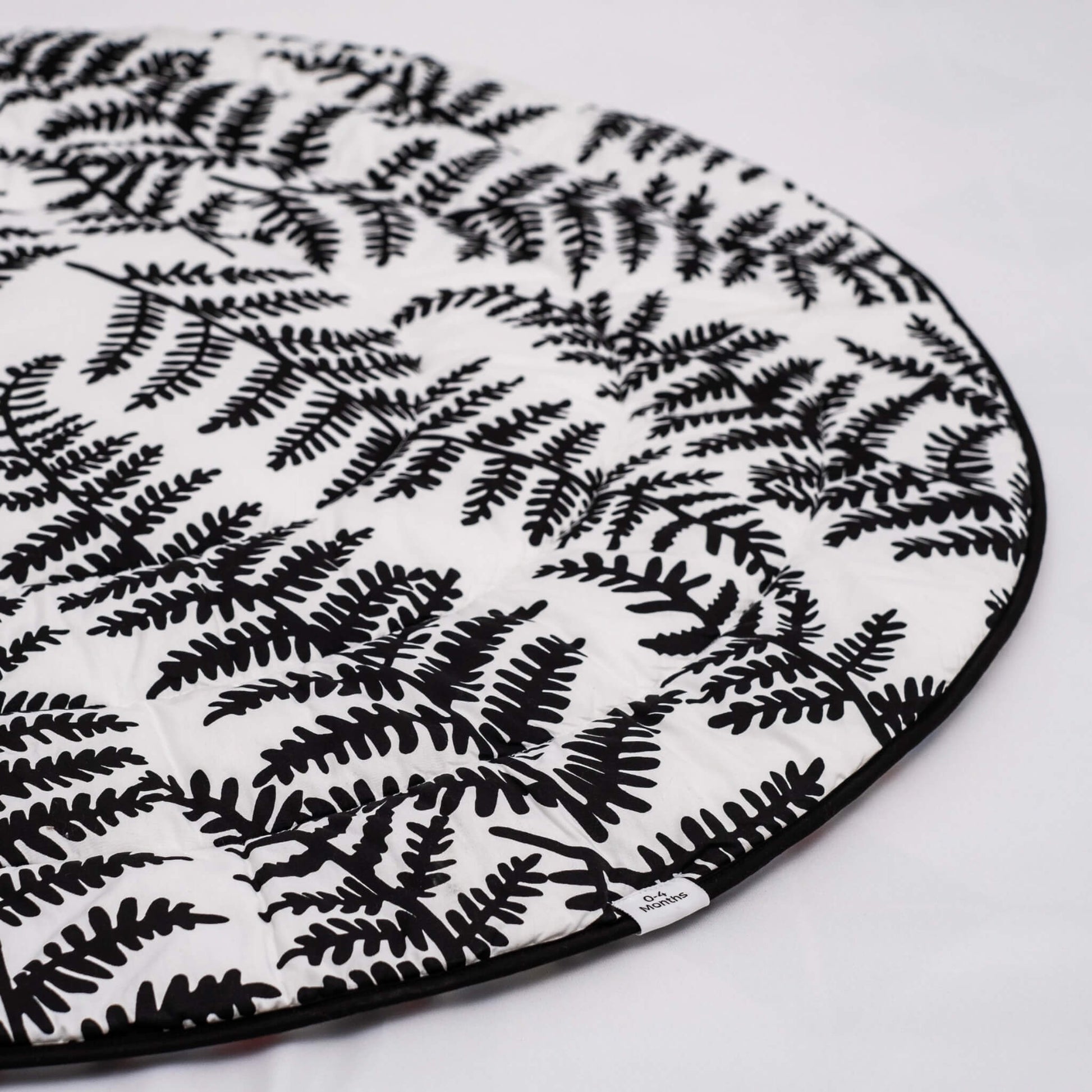 Detail of softly quilted organic cotton surface with black leaf shapes stitched across white background.