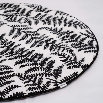 Detail of softly quilted organic cotton surface with black leaf shapes stitched across white background.