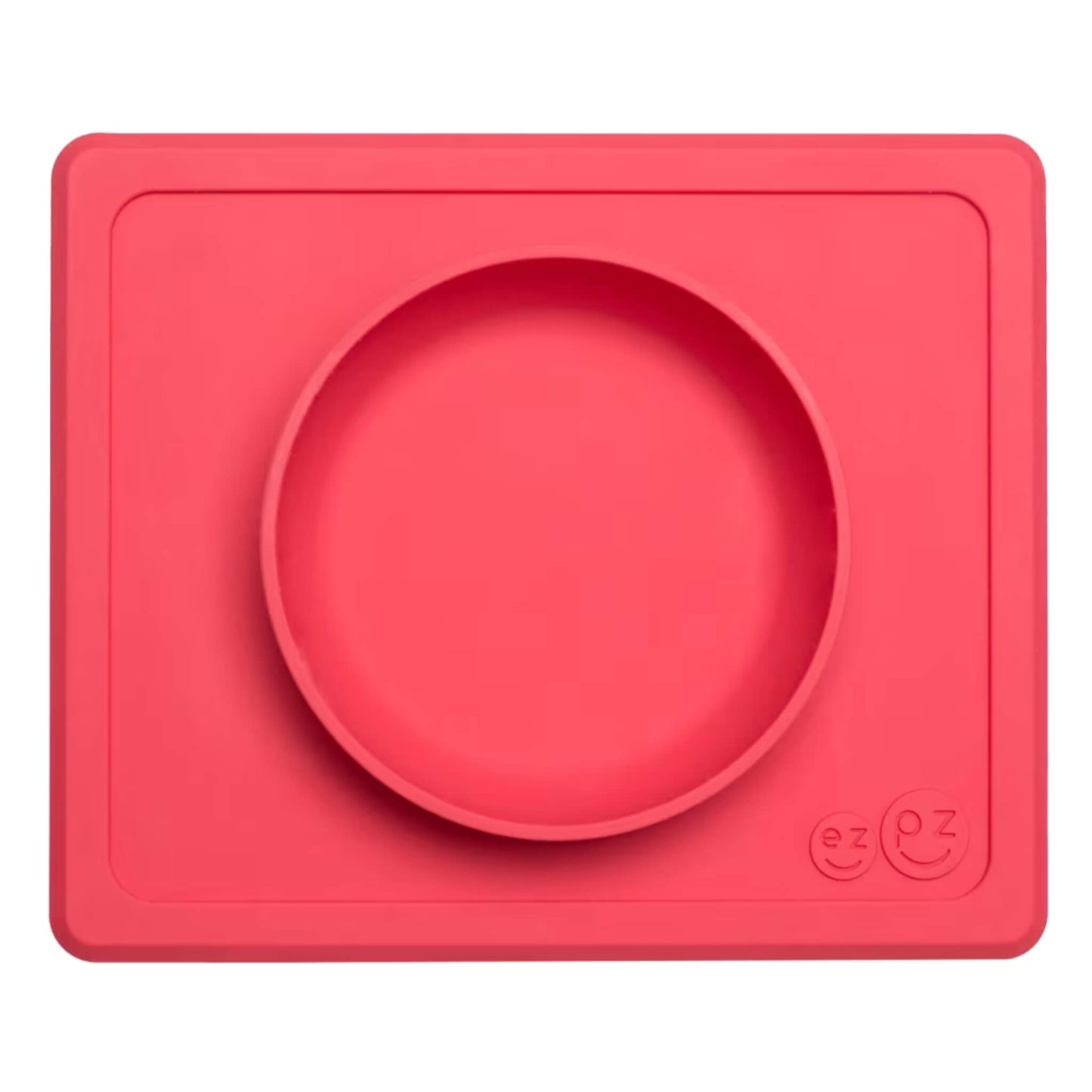 ezpz Mini Bowl in coral shown from above, a silicone suction bowl built into a rectangular placemat to reduce spills during baby mealtimes.