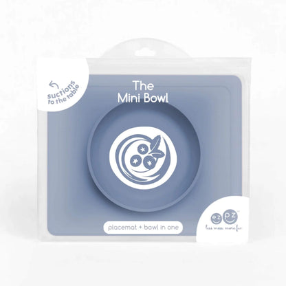 Indigo silicone mini suction bowl with built-in placemat, shown inside retail packaging with clear front display.