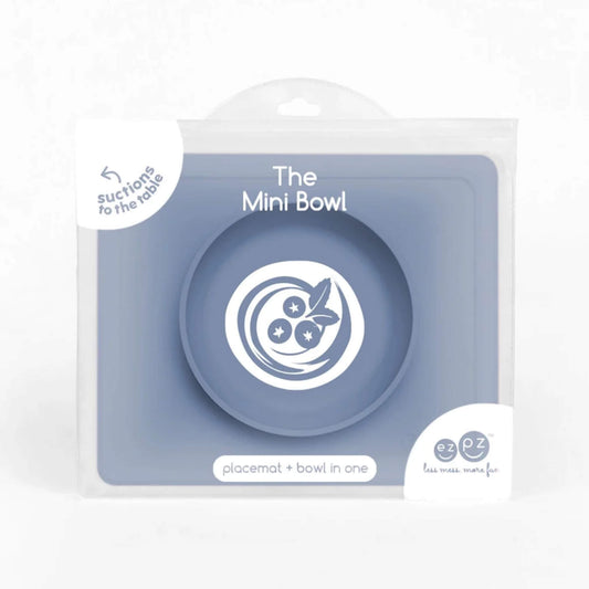 Indigo silicone mini suction bowl with built-in placemat, shown inside retail packaging with clear front display.