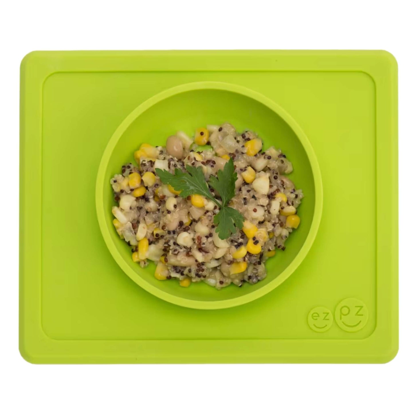 Lime silicone suction bowl with built-in placemat, filled with quinoa, sweetcorn and herbs, shown from above.