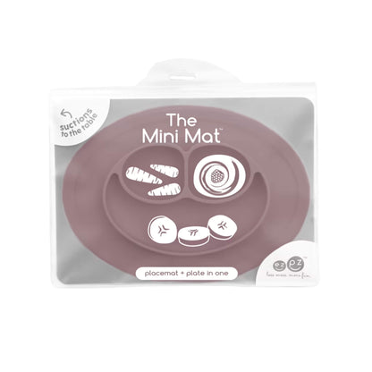 Clear storage case displaying The Mini Mat in mauve, labelled as a suction placemat and plate in one, with simple food illustrations printed on the packaging.