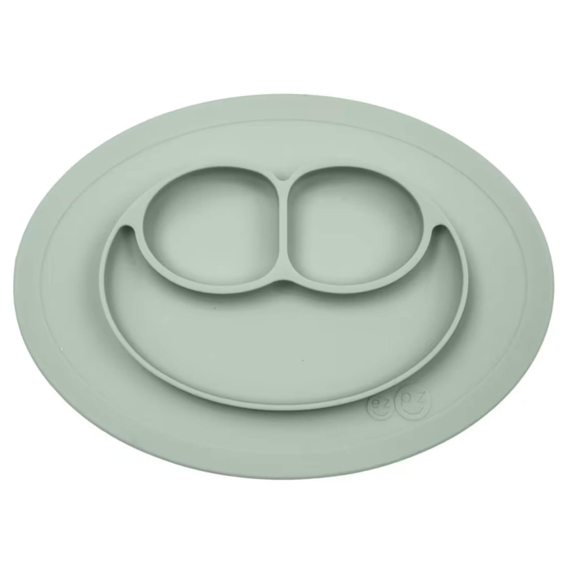 Ezpz Mini Mat in sage green silicone, an all-in-one suction placemat and baby plate with three divided sections arranged in a smile design.