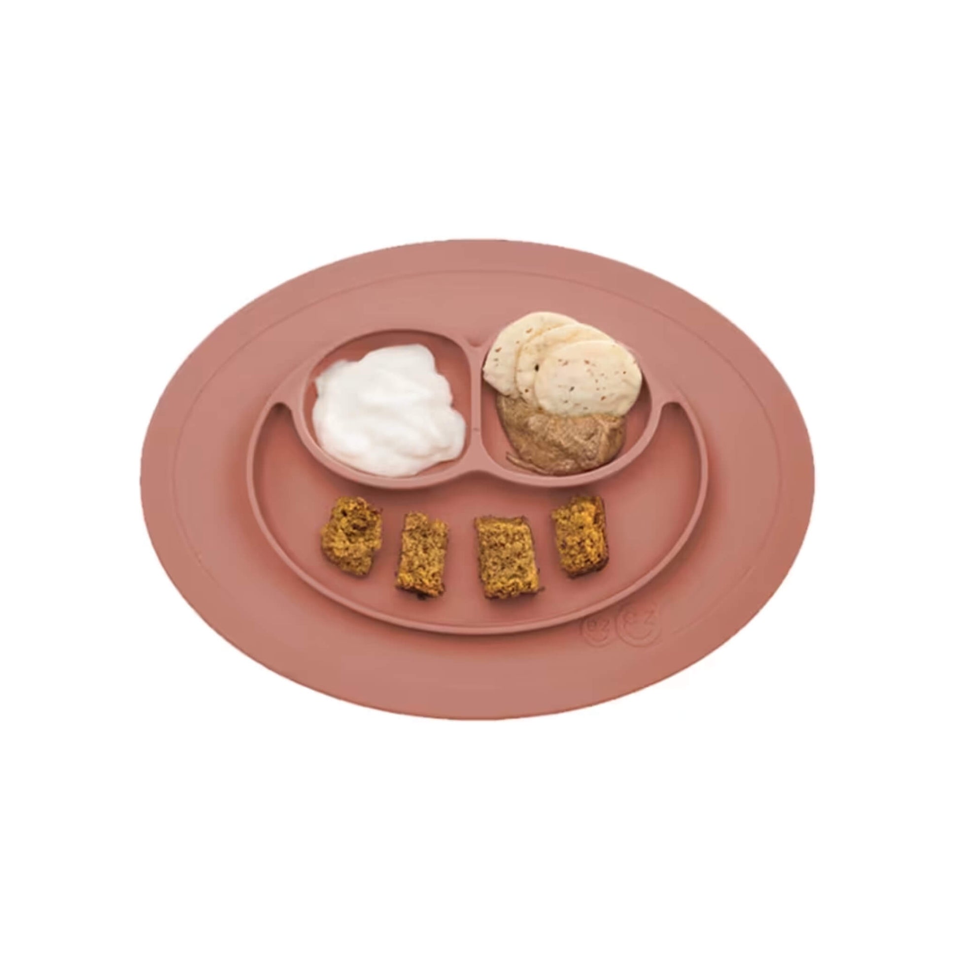 Sienna silicone suction placemat with three divided sections containing food including banana slices, yogurt, and small pieces of baked bread.