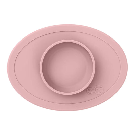 ezpz Tiny Bowl in blush pink with an oval silicone mat and raised central bowl, shown empty from above.