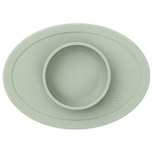 ezpz Tiny Bowl in sage green with an oval silicone mat and raised central bowl, shown empty from above.