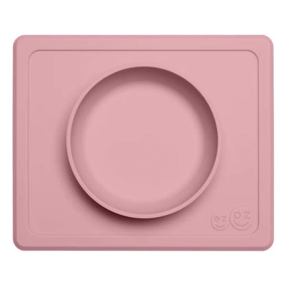 Ezpz Mini Bowl in blush pink, a silicone placemat and bowl in one that suctions to the table to reduce spills during toddler mealtimes.