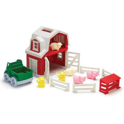 Toy farm set arranged with the barn doors open and animals placed inside and around the barn, showing sheep in the loft and pigs in the pen area.