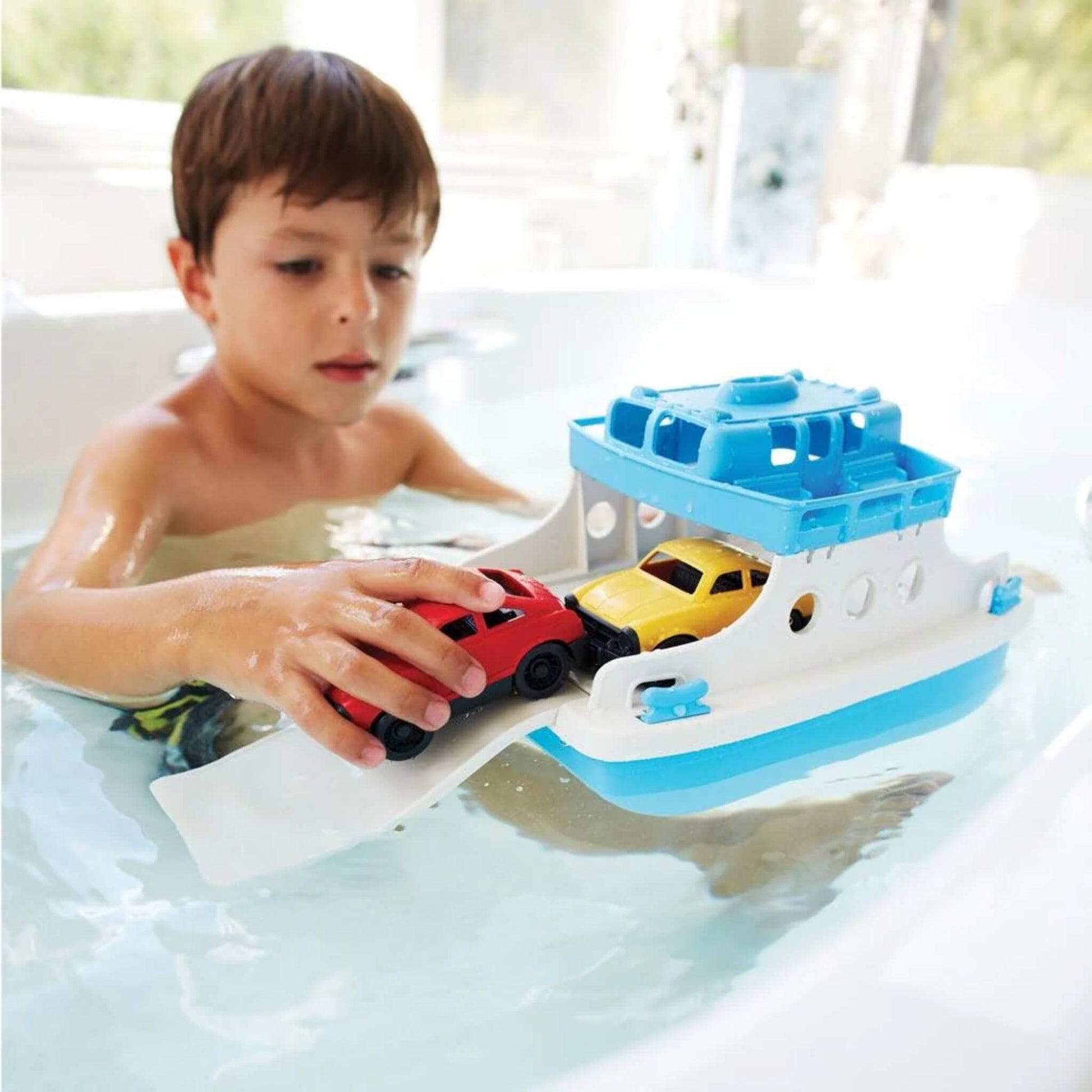 Young child playing with the Ferry Boat in the bath, guiding the mini cars onto the ramp for realistic, water-based roleplay.