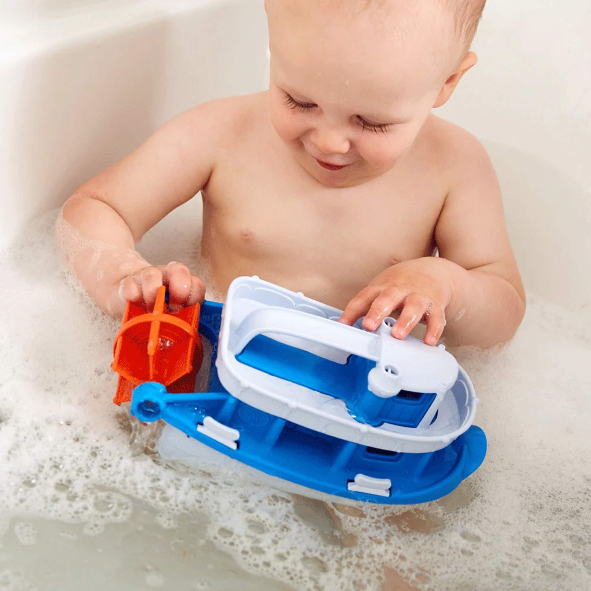 Child turning the orange paddle wheel on the Paddle Boat, exploring how it spins in the bathwater.