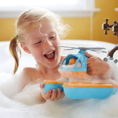Young child in a bubbly bath, holding the Seacopter and smiling, with foam covering parts of the toy as she plays.