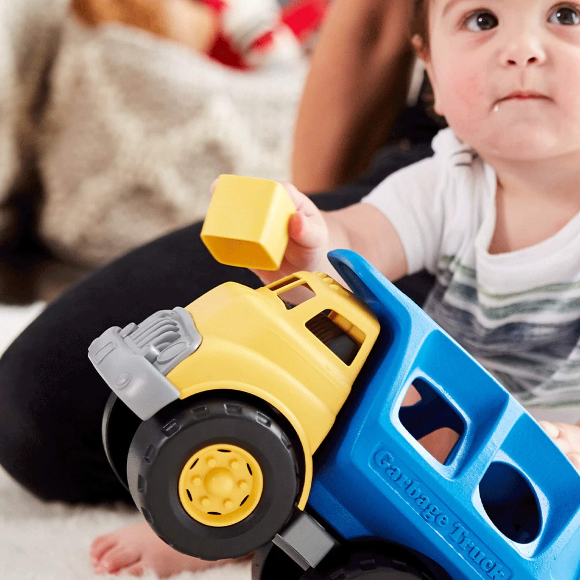 Close-up of a young child holding the yellow cab and pushing the green shape into the top of the truck.