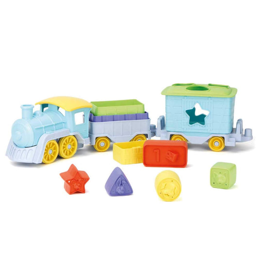 Green Toys Stack & Sort Train Set shown with pastel blue engine, two carriages, colourful stacking blocks and shape pieces arranged in front.