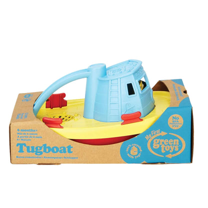The Green Toys Tugboat shown packaged in its original cardboard box with branding and age guidance visible.