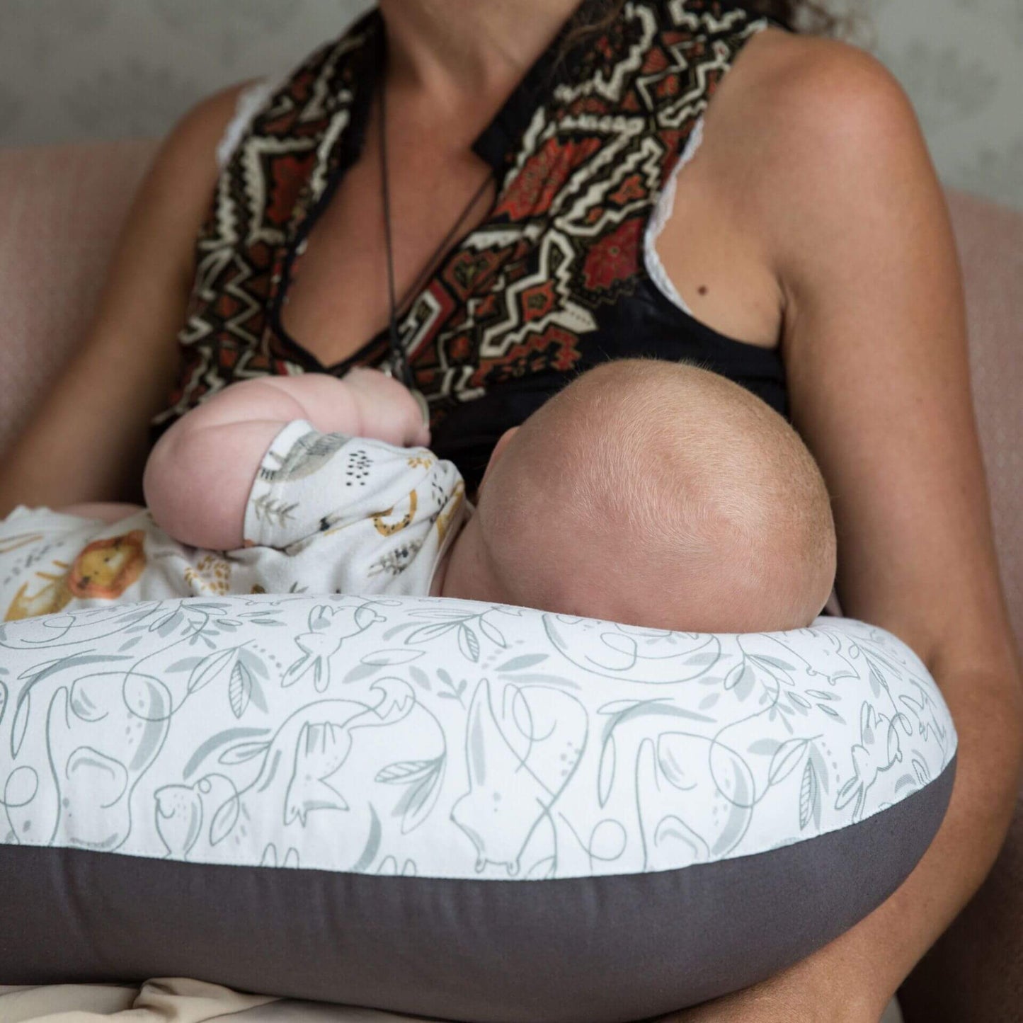 Mother breastfeeding a baby with a feeding pillow across her lap, providing cushioned support during feeding.