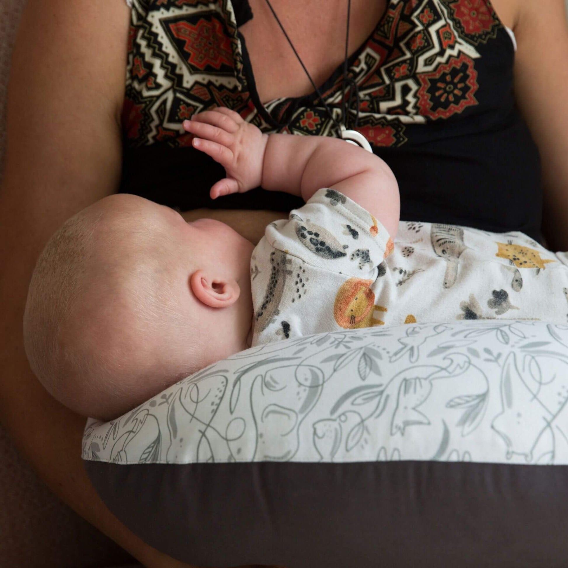 Baby lying comfortably on a feeding pillow during bottle feeding in parent’s arms.