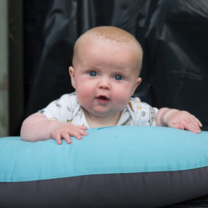 Baby during tummy time resting on a supportive feeding pillow in reef blue and charcoal.