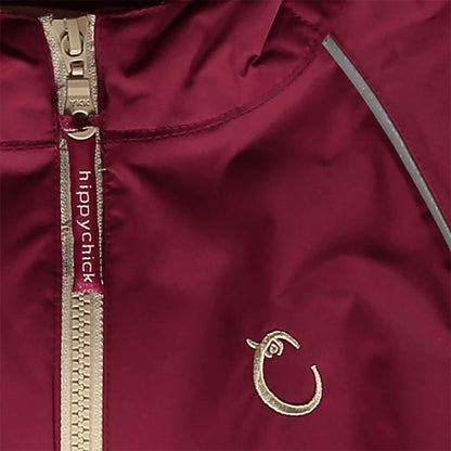 Close-up of raspberry waterproof fabric with beige zip, showing reflective piping and embroidered Hippychick brand logo detail.
