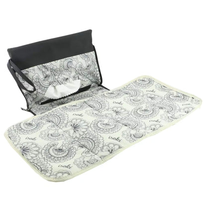 Full view of a baby changing mat fully unfolded, featuring a black and white floral print and softly padded sections for comfort.