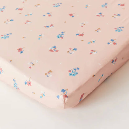 Kabode Blossom Organic Cotton Fitted Sheet laid flat, showing soft pink fabric with small scattered floral motifs and neatly fitted corners.